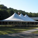 30x60 Pole Tent set with tables and chairs for a corporate event with american flag in the background.