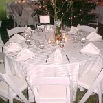 Simple setting with white party chairs and white stripe tablecloths