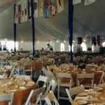 Large pole tent with decorated center poles, Full table settings with linens and white party chairs