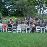 White Party Chairs set for Wedding Ceremony in a Garden with Guests